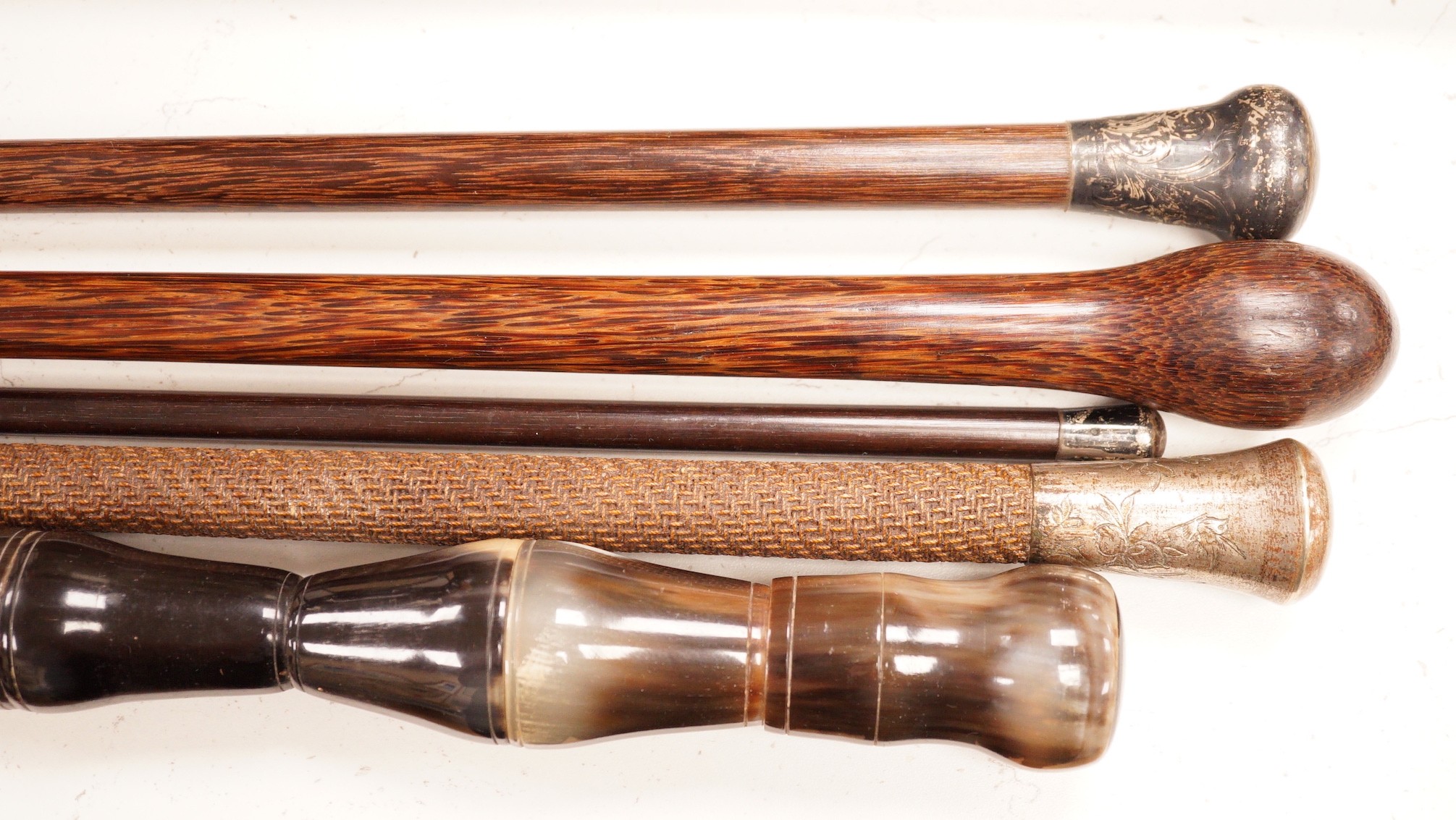 Five assorted walking canes / to include an amboyna example, a sectional horn example, two silver topped etc.